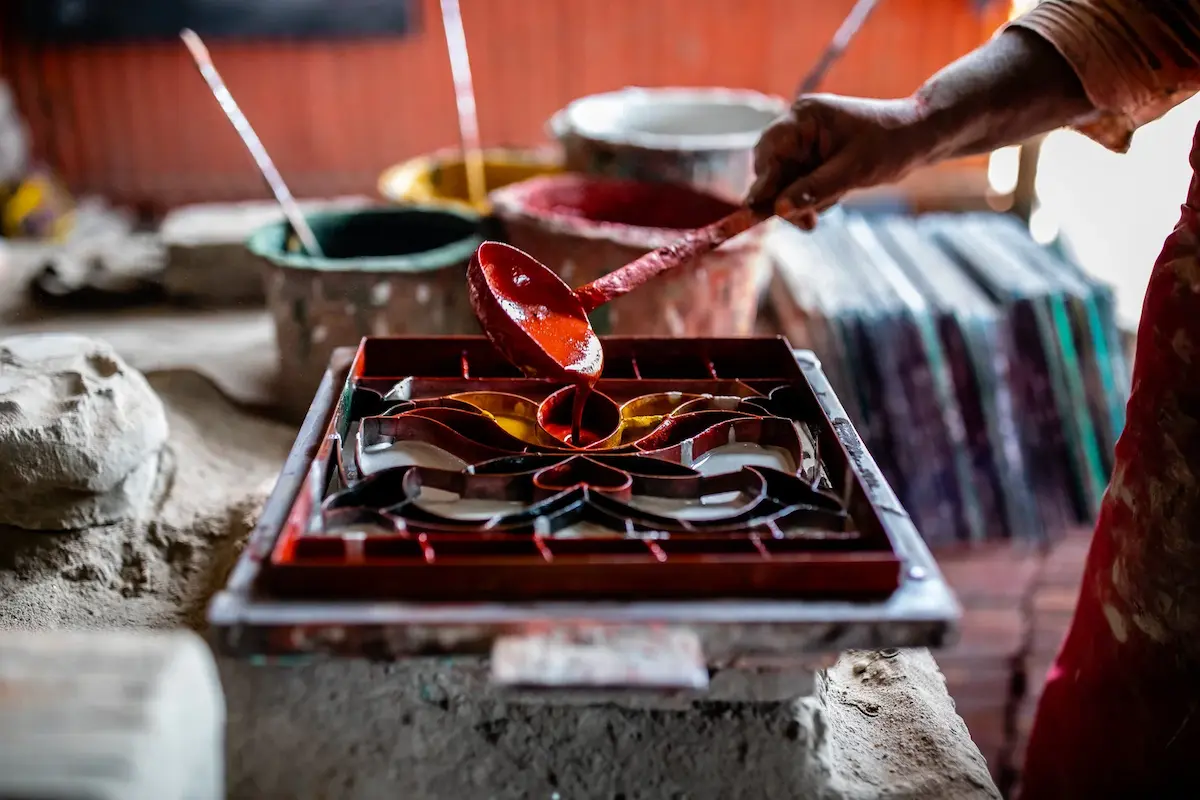 Artisan filling colors into handmade Athangudi tiles